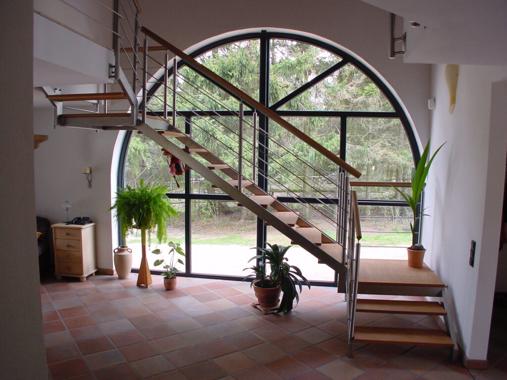 Individuelle Edelstahltreppe in der Galerie eines Hauses mit Holzstufen und Holzhandlauf